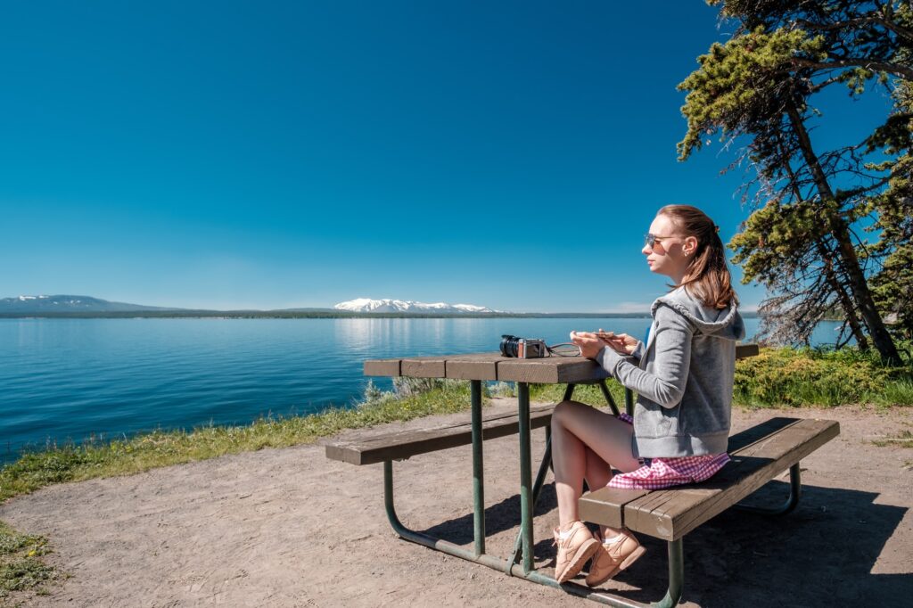 Woman tourist having a breakfast by Yellowstone Lake